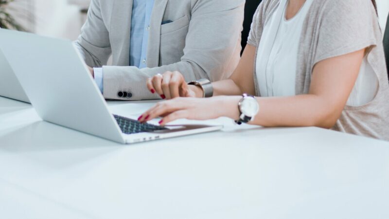 Two people in an office typing on laptops