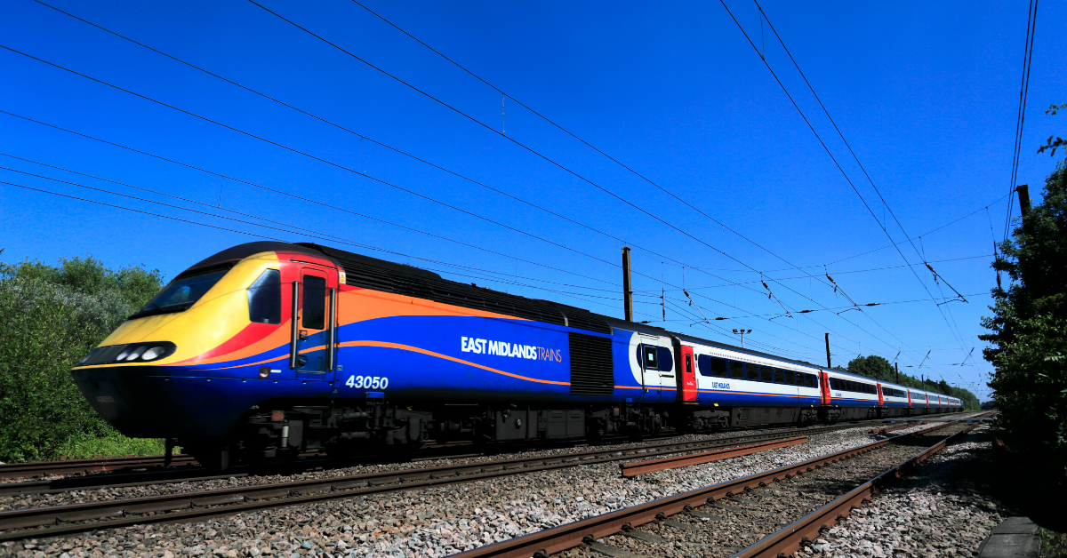 Image shows an eight-carriage East Midlands Trains train moving along a railway track. The train is decorated with yellow, red, orange and blue streaks of colour.