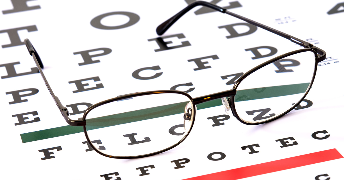 A pair of glasses sit on top of white paper, emblazoned with large print text.