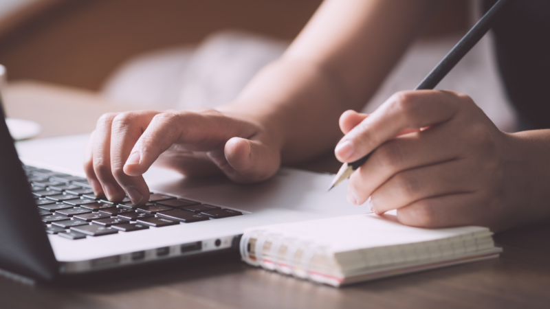 Taking notes next to laptop