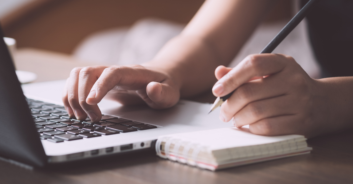 Taking notes next to laptop