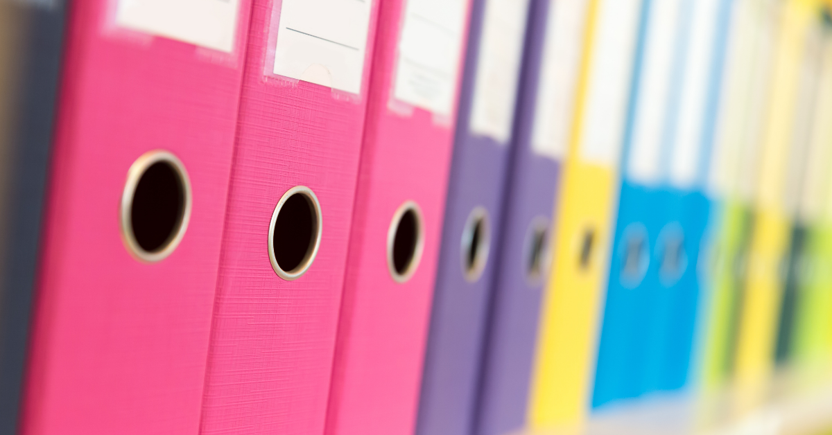 Image shows a selection of brightly coloured ring-binder folders on a shelf.